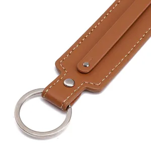 Detail of caramel brown lychee leather keychain with silver metal ring and white stitching
