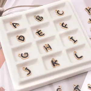 Detailansicht von schwarzen Emaille-Buchstabenanhängern A-L mit goldenem Rand für DIY