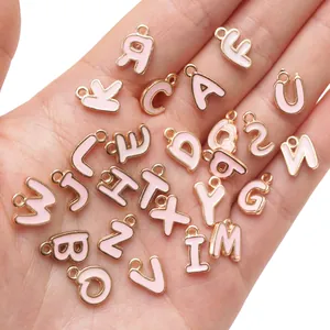Rosa Emaille A-Z Buchstabenanhänger in der Hand für DIY Schmuck mit Goldrand