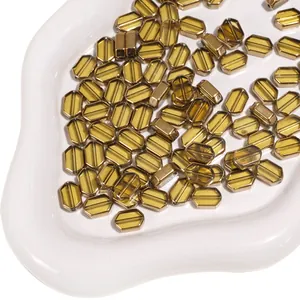 Macro shot of amber glass beads with gold trim and parallel grooves in a white tray