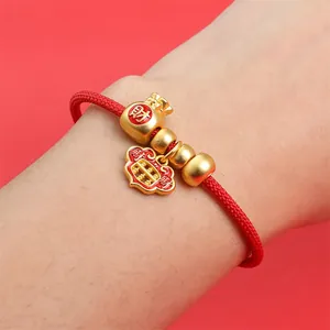 Gros plan d'un bracelet tressé rouge avec pendentifs sac de fortune et abaque
