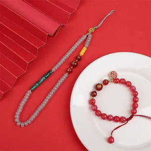 Detail of red agate beads with gold Fu and Lu characters on traditional fan background