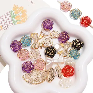 Lot de perles en acrylique avec roses à bord doré et pendentifs en métal dans un plateau