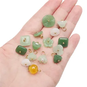 Assorted jade-style pendants in various shapes with gold loops shown on hand palm