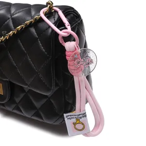 Pink nylon woven keychain with acrylic floral tag on a black quilted chain bag