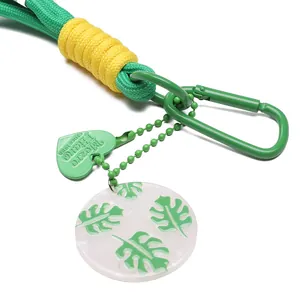 Detail of woven nylon keychain with green carabiner, heart charm, and monstera leaf pendant
