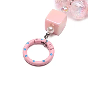 Close-up of pink polka dot spring ring and pearlescent beads for DIY keychain making