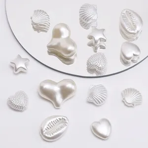 Macro shot of pearlized heart and shell shaped ABS loose beads on a reflective mirror