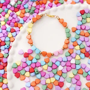Makroaufnahme bunter Acryl-Herzperlen auf weißem Keramikteller für DIY-Schmuck