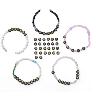 Detail of DIY bracelets with black acrylic letter beads and gold letters on white background