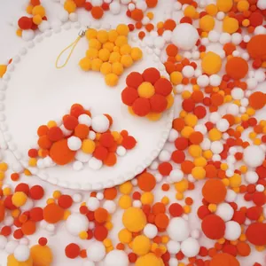 Pompons élastiques DIY orange et jaune, disposés en formes d'étoiles et de fleurs