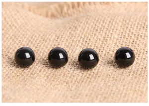 Macro shot of four polished black agate beads with glossy finish on linen background