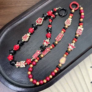 Traditional Chinese lion dance charms and beads on festive red and black phone straps