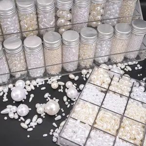 Dettaglio macro di varie perle ABS bianche a goccia e rotonde in piccoli barattoli