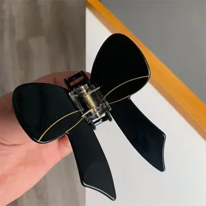 Elegant black acetate butterfly hair claw clip with gold accents for stylish hairstyling