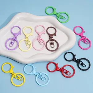 Close-up of multi-colored alloy lobster clasps and key rings on a white ceramic tray