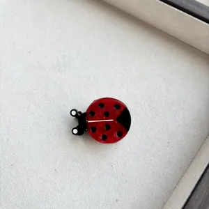 Detail of cute red ladybug hair clip with black spots made of glossy resin material