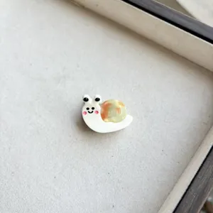 Detail of cute resin snail hair clip with amber shell and cream body for girls