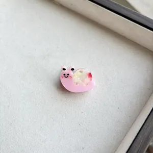 Macro shot of pink resin snail hair clip with colorful shell and cute smiling face details