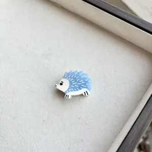 Macro shot of a cute light blue resin hedgehog hair clip on a soft gray jewelry tray