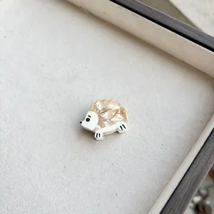 Detailed close-up of a cute hedgehog resin hair clip with champagne and white finish