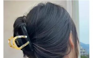Detail of elegant black and amber tortoiseshell hair claw clip in a half-up hairstyle