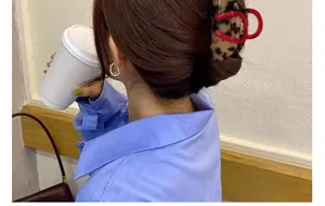 Detail view of a leopard print claw clip with a red frame in a chic Korean hair bun