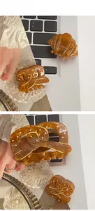 Détail de grandes pinces à cheveux ambrées en forme de croissant avec liseré doré