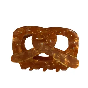 Pince à cheveux en forme de bretzel ambré avec texture marbrée sur fond blanc