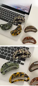 Detail showing various colors of large acetate claw clips on a laptop desk setup
