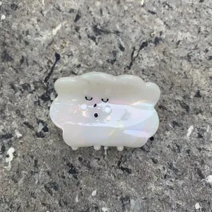 Pearly white cloud hair claw clip with cute cartoon face on stone background