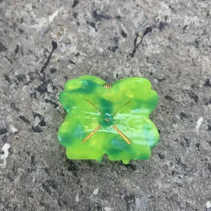 Detail of green clover acetate hair claw clip with golden butterfly metal ornament