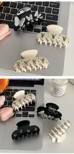 Detailed close-up of large hair claw clips with rhinestones and 3D butterfly designs