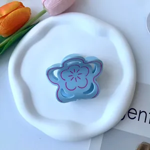 Dettaglio della molletta per capelli a fiore azzurro con contorni rosa rossastri