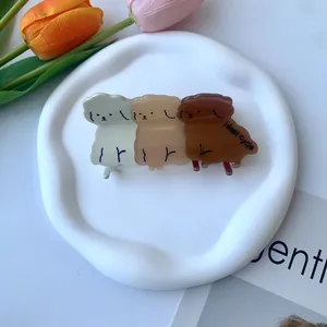 Dettaglio di tre mollette per capelli a forma di cucciolo in resina su vassoio in ceramica