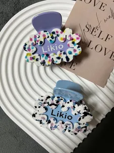 Dettaglio di mollette per capelli a onde in acetato viola e azzurro con scritta Likio