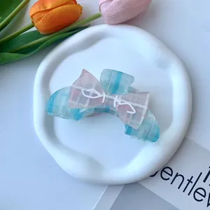 Dettaglio molletta per capelli a scacchi blu con fiocco rosa su un vassoio bianco