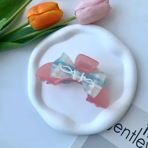Dettaglio molletta per capelli rosa in acetato con fiocco a quadretti blu