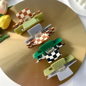 Set of four large checkered hair clips in various colors on a luxury metal tray with tulips