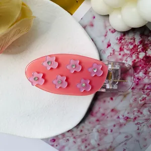 Détail d'une pince à cheveux rose en acrylique avec fleurs délicates et petits strass
