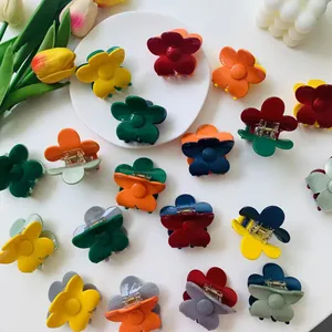Flat lay of colorful flower hair claw clips on white surface with tulip decorations