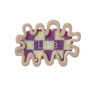 Pink wavy hair clip with purple checkerboard pattern and Like text on white background