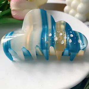 Macro shot of cloud-shaped hair claw with blue stripes and sparkling rhinestones