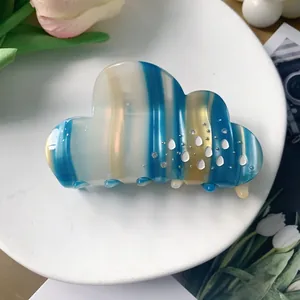 Close-up of cloud-shaped acetate hair claw clip with blue stripes and rhinestone details