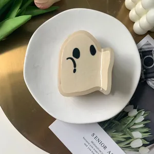 Detail of a cream ghost-shaped acetate hair claw clip on a minimalist decorative tray