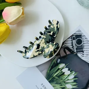 Detailansicht der Camouflage-Haarklammer aus Acetat auf einem weißen Dekoteller
