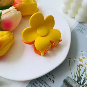 Close-up of yellow flower hair claw clip with matte finish on a white decorative plate