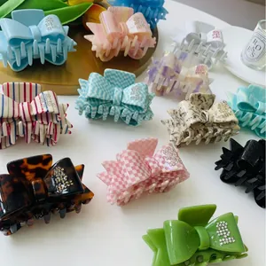 Elegant acetate bow hair claws with rhinestone accents in checkered and marble patterns