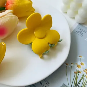Close-up of a yellow flower hair claw clip on a decorative white ceramic plate