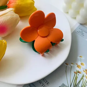Macro detail of orange flower hair claw clip with green base on elegant display